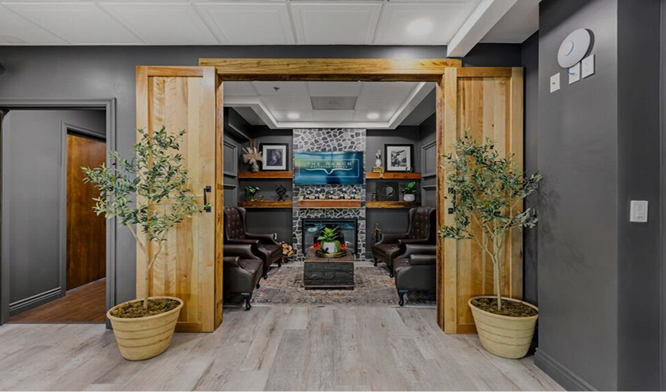 Foyer with wooden doors, potted plants, and a view into a living room - Integrated Clinical Excellence