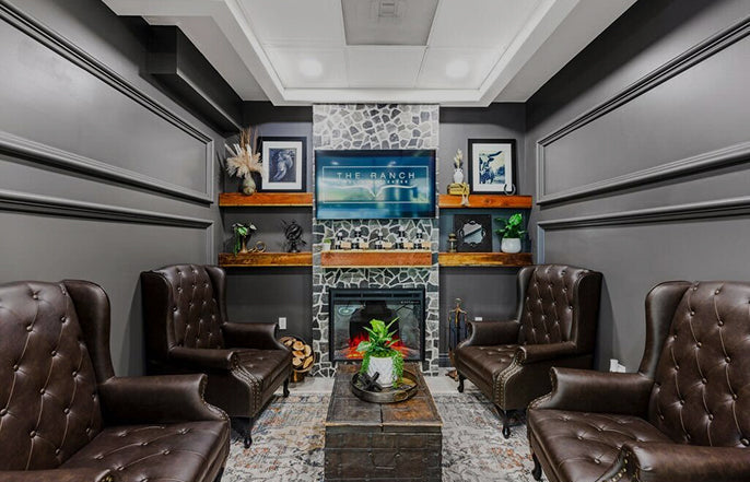 Luxury living room with brown leather chairs, a fireplace, and decorative elements.