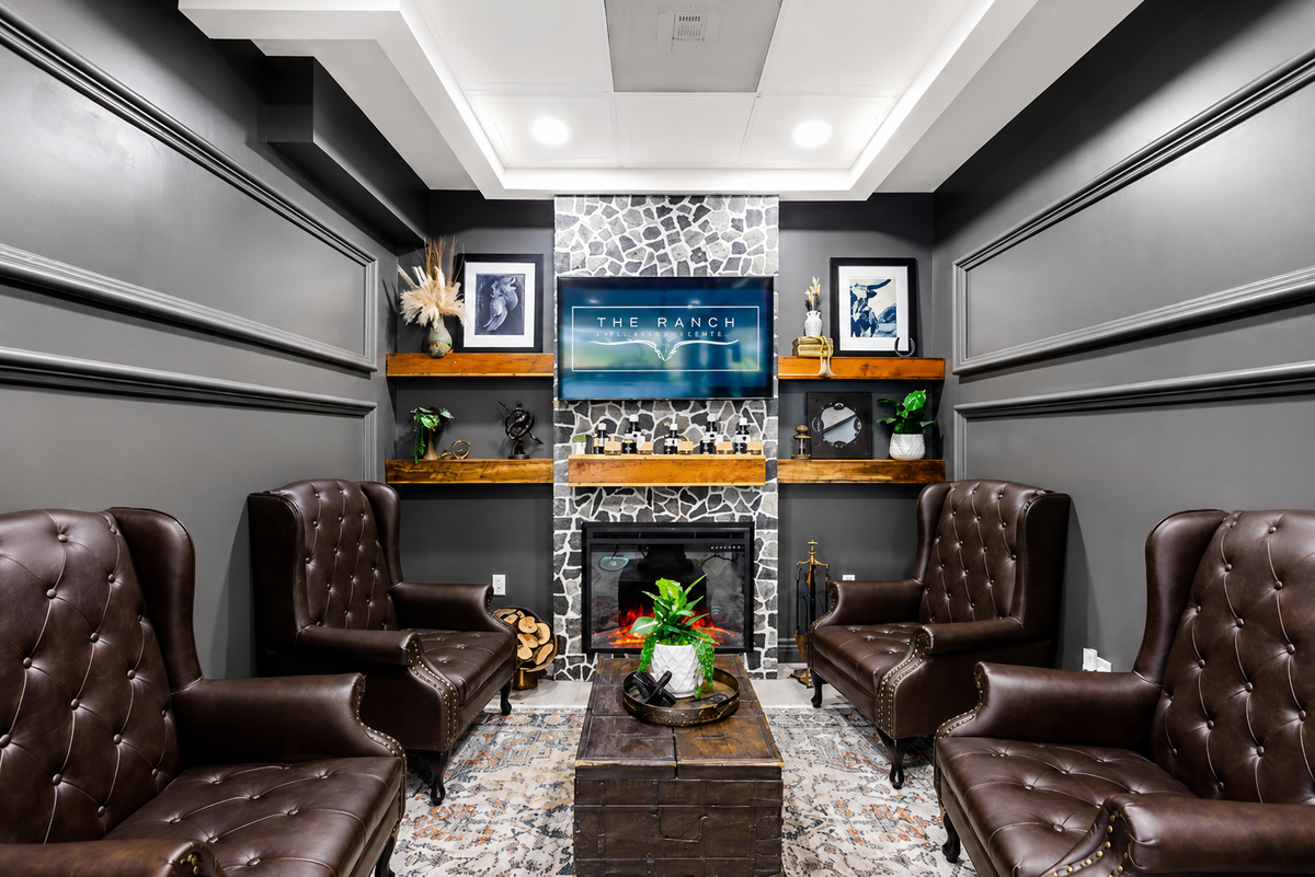 Modern home theater with brown leather chairs, a fireplace, and a TV.