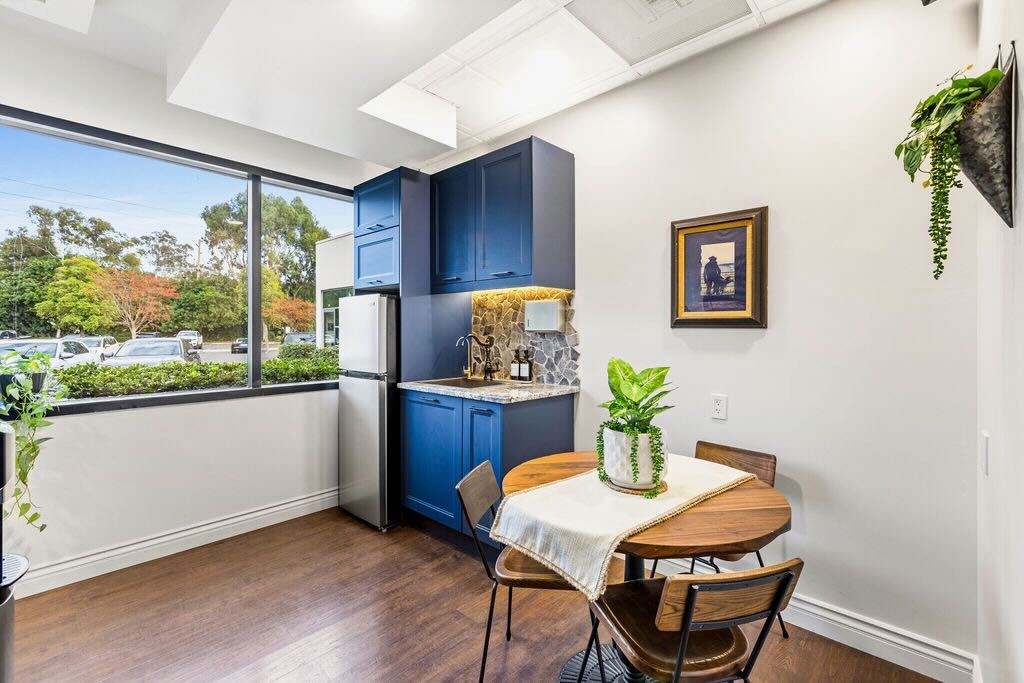 Modern kitchen with blue cabinets, wooden table, and chairs.