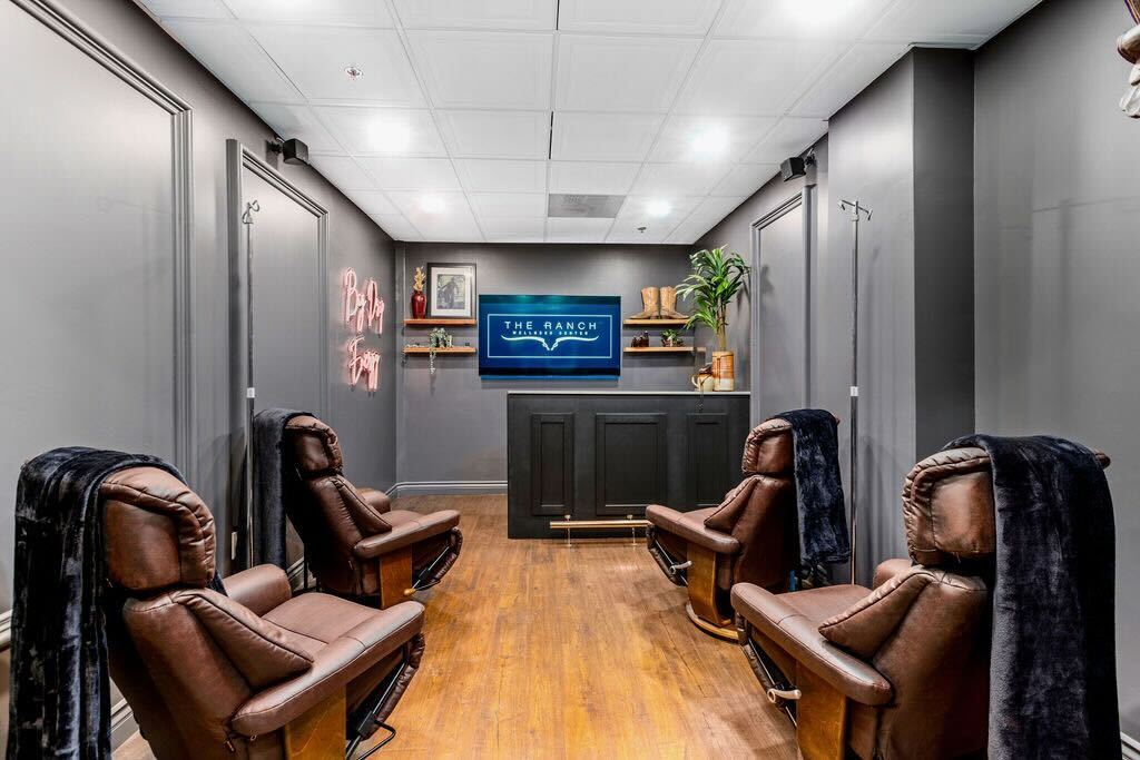 Modern room with brown leather chairs, a TV, and shelves.